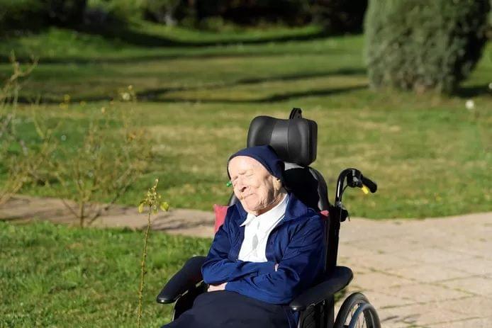 Un día antes de cumplir 117 años, en febrero de 2021, sor André disfrutaba del sol en su silla de ruedas. Créditos AFP